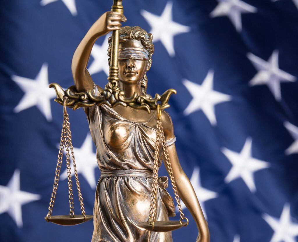 Lady justice statue with background image of the american flag