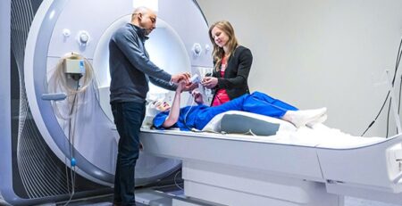 Two researchers working with a student on a MRI machine