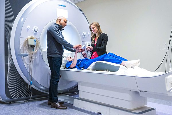 Two researchers working with a student on a MRI machine