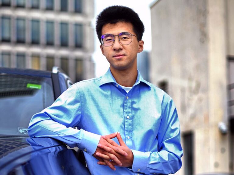 Dr. Haoxin Wang poses next to a vehicle in downtown Atlanta