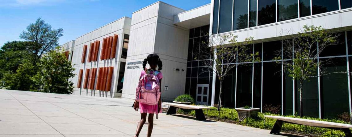 young african american school girl walking towards school