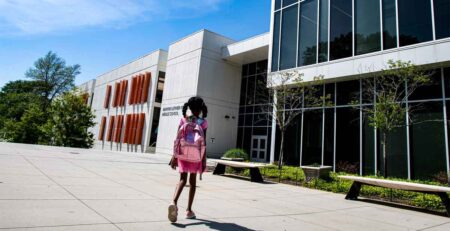 young african american school girl walking towards school