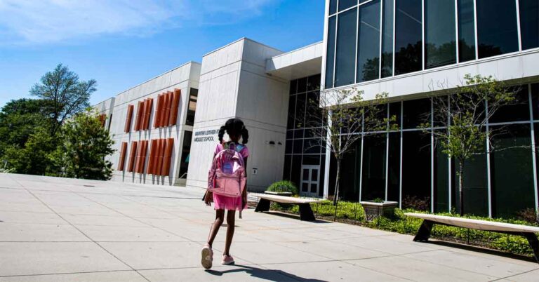 young african american school girl walking towards school