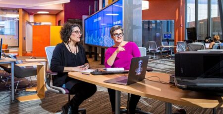 Two caucasian women working together in the library