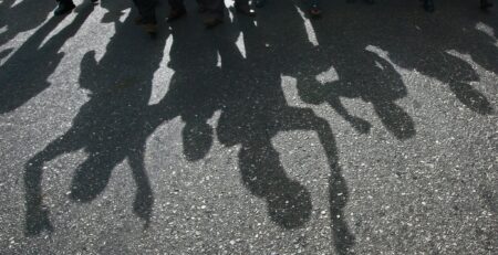 Protesters cast a shadow as they march on a street