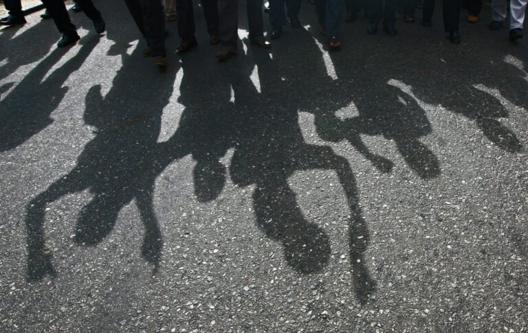 Protesters cast a shadow as they march on a street