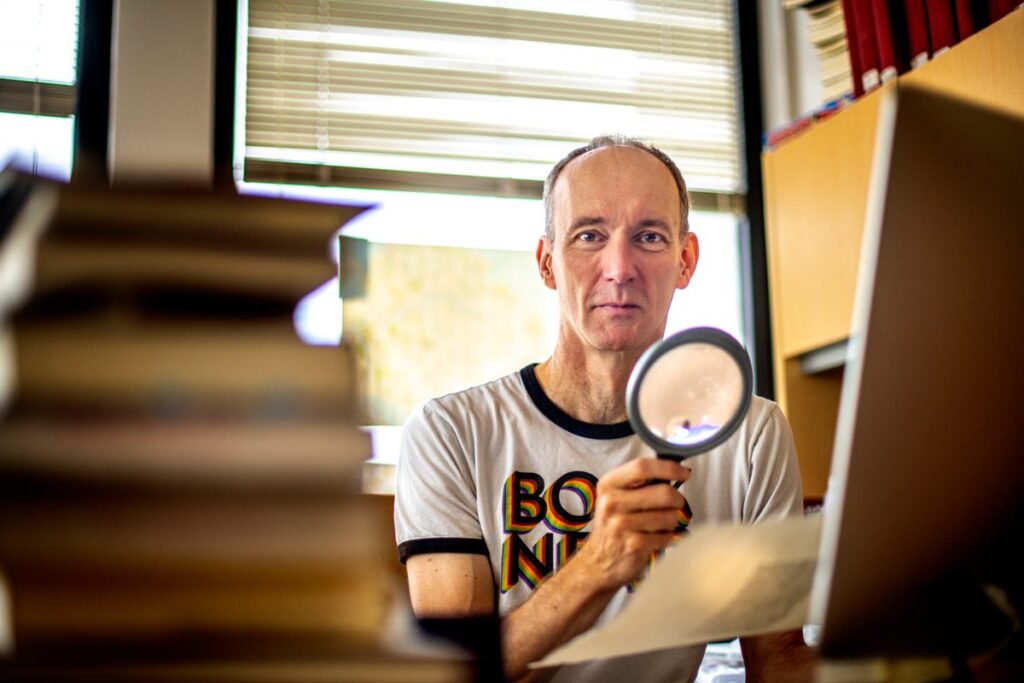 Nick Wilding holding a magnifying glass in his Georgia State office.