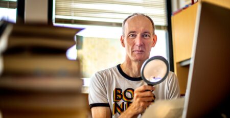 Nick Wilding holding a magnifying glass in his Georgia State office.